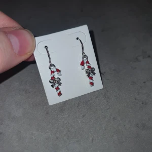 Örhängen - Charmiga örhängen med hängande design, dekorerade med små röda och vita pärlor samt silverfärgade detaljer. Perfekta för att ge en färgklick till din outfit.