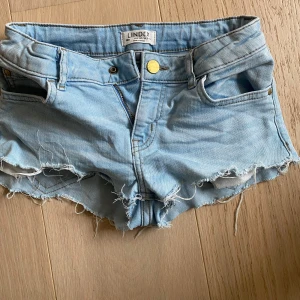 Ljusa jeansshorts från Lindex - Snygga ljusa jeansshorts från Lindex med fransiga kanter och klassisk femficksdesign. Perfekta för varma sommardagar. De har en knapp och dragkedja framtill för enkel stängning. Säljer då de är för små!🩷