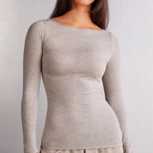 Grå långärmad topp - Snygg och enkel grå långärmad topp i mjukt material. Perfekt för lager-på-lager eller att bära som den är. Den har en tight passform som framhäver figuren.