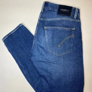 Dondup Luxury Denim Jeans – W32 - Säljer ett par stilrena och klassiska Dondup Luxury Denim jeans i storlek W32. De är slim fit!               Dondup är känt för sitt italienska hantverk och sina exklusiva materialval, och dessa jeans är inget undantag.  Produktinformation: 	•	Storlek: W32 	•	Längd: 97 cm 	•	Midja: 39 cm 	•	Färg: Klassisk blå denim 	•	Material: Premium denim – slitstarkt och bekvämt 	•	Tillverkade i: Italien  Skick: Väldigt bra, knappt använda. Pris: 899 kr (pris kan diskuteras). Nypris över 4000kr!!! 