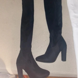 Svarta overknee boots med klack - Snygga svarta overknee boots i mocka med hög klack och dragkedja på sidan. Perfekta för en stilren look.
