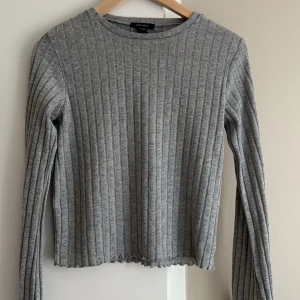 Grå ribbad tröja från new Yorker  - Säljer en stilren grå ribbad tröja från new yorker. Tröjan har långa ärmar och en rund halsringning, perfekt för kyligare dagar. Den är enkel att matcha med olika outfits och ger en avslappnad look. (EGNA BILDER PRIVAT)