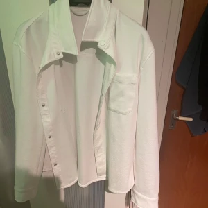 Vi overshirt från zara - Säljer en stilren vit overshirt med knappar framtill. Den har en klassisk krage och en bröstficka. Perfekt för lager-på-lager-stil. Passar till många olika outfits!
