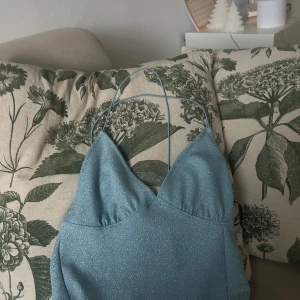 Glittrig blå klänning - Snygg glittrig blå klänning med smala axelband och v-ringad design. Perfekt för en festlig kväll! ✨Aldrig använd 😊