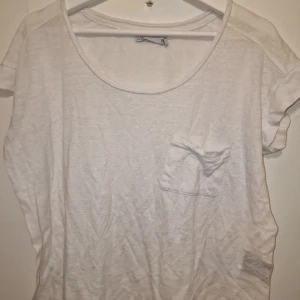 Vit t-shirt med bröstficka - Perfekt för en avslappnad look. Passar bra till jeans eller shorts. 