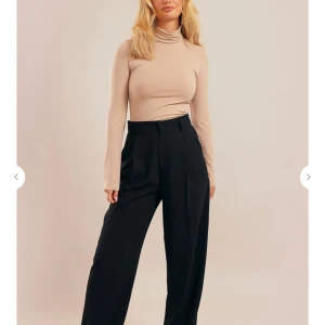 Beige polotopp från Chiquelle - Snygg och stilren beige polotopp med lång ärm. Perfekt för både vardag och fest. Den är tight och sitter riktigt bra på kroppen, vilket ger en elegant look. Materialet ser ut att vara mjukt och bekvämt.