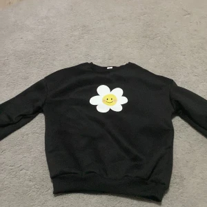 En svart blomtröja - Storlek är 140 eller 10år. Den är ny och har använts en eller två gånger. 