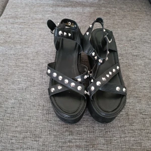 Svarta sandaler med nitar - Säljer ett par svarta sandaler med nitar. De har en platåsula och remmar med silverfärgade nitar som ger en edgy look. andvända 1 gång 🖤 obs betalning sker via swish 