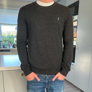 Polo Ralph Lauren - stickad tröja merinoull - Nyskick, väldigt skön stickad tröja i mörkgrå färg med ljusgrå logga på bröstet, slim fit, originalpris cirka 2000kr, skriv gärna om du har frågor