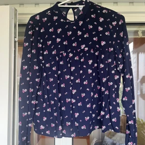 Söt mörkblå blus - Från Divided, HM. Stlk 38 men mer som en 34-36. Mörkblå. Små blommor. Två knappar i nacken. 