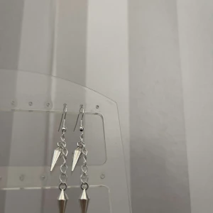Silvriga örhängen med kedja och spetsdetalj - Snygga och trendiga silvriga örhängen med en kedja och spetsiga detaljer. Perfekta för att ge en edgy touch till din outfit. De är lätta och bekväma att bära hela dagen.