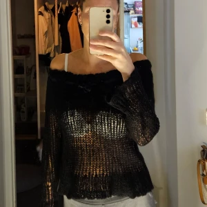 Svart stickad tröja från Saint Tropez -  Nyskick Säljer en superfin svart offshoulders  stickad tröja från Saint Tropez. Den har en mysig och lite luftig stickning med långa ärmar. Detaljerna med en rosettoch strasspärlor  vid halsen ger den en söt touch. Perfekt för höst och vinter när du vill vara både varm och stilren. 🖤