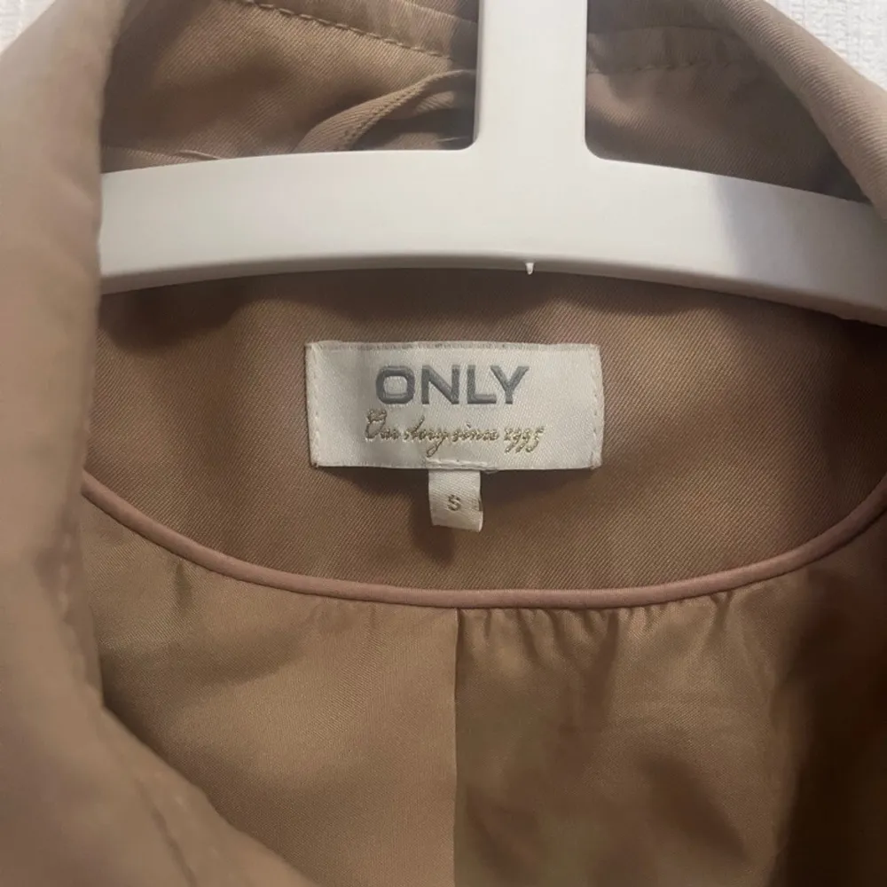 En lättanvänd beige kappa (trenchcoat) från ONLY. Nypris:500kr . Jackor.