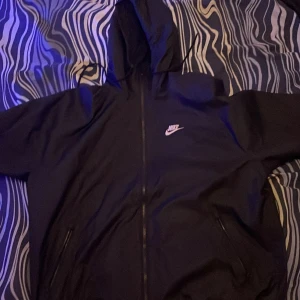 Svart jacka från Nike - Denna jacka är rätt så använd men vill gärna bli av med den den finns ett litet litet hål nere på en av armarna men den är lätt att sy igen säljer denna billigt pågrund av att den är rätt använd storlek S men passar M kan passa L