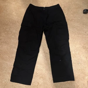 Svarta cargopants i storlek XL - Säljer ett par svarta cargopants med praktiska fickor på sidorna. Byxorna har en loose passform och är perfekta för en avslappnad stil. Tillverkade i ett slitstarkt material som passar bra för olika aktiviteter. Använda 1 gång
