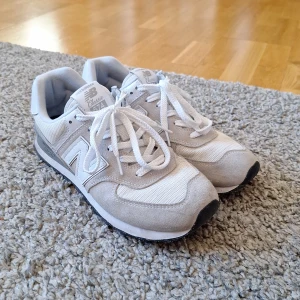 New Balance 574 skor - Gråa/vita New Balance 574 skor. Skorna är i bra skick förutom lite fläck på vissa ställen och har inga defekter. Köpt i December. Skick: 8/10