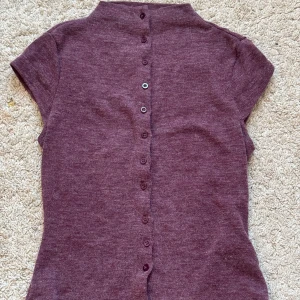 Vinröd topp från Shein - Säljer en vinröd topp från Shein med korta ärmar och knappar längs ryggen. Perfekt för en stilren look. Toppen är gjord i ett mjukt material som känns skönt mot huden.