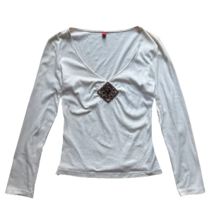 Vit vintage långärmad topp från Esprit - Säljer en stilren vit långärmad topp från Esprit med en v-ringning och dekorativ detalj i form av ett broderat mönster med pärlor framtill. Perfekt för att ge en elegant touch till din outfit. Passar en S eller M bäst! 