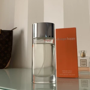 Clinique Happy Parfym - Fräsch och upplyftande parfym från Clinique i en elegant flaska med silverfärgat lock. Doften kommer i en 100 ml (ca 90% kvar) flaska och levereras i en livfull orange kartong. Perfekt för att ge en känsla av glädje och energi. (Nypris 1340kr)
