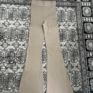 Beige vida byxor - Snygga beige byxor med vida ben och hög midja. Perfekta för en stilren look. Materialet är mjuk och bekväm.