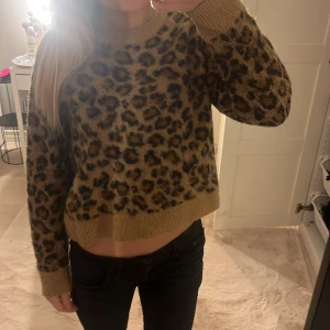 Leopardmönstrad tröja från H&M - Säljer en snygg leopardmönstrad tröja från H&M. Tröjan har en beige bas med svarta och bruna fläckar. Den är långärmad och har ribbade muddar vid ärmslut och nederkant. Perfekt för att ge din outfit en trendig touch! 🐆