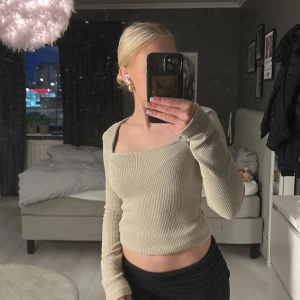 Beige ribbad topp från Gina Tricot - Säljer en snygg beige ribbad topp från Gina Tricot. Toppen har en fyrkantig halsringning och långa ärmar, perfekt för en stilren look. Den är croppad och passar bra till både jeans och kjol.