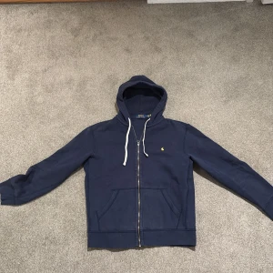 Mörkblå hoodie från Polo Ralph Lauren - Säljer en snygg mörkblå hoodie från Polo Ralph Lauren som är i bra skick, inga defekter. Hoodien är i strl M.