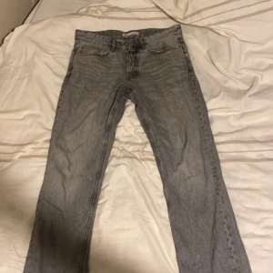 Grå jeansbyxor - Snygga grå jeansbyxor med en klassisk straight passform. De har en midwaist design och är perfekta för en avslappnad stil. Byxorna har fem fickor och stängs med dragkedja och knapp.