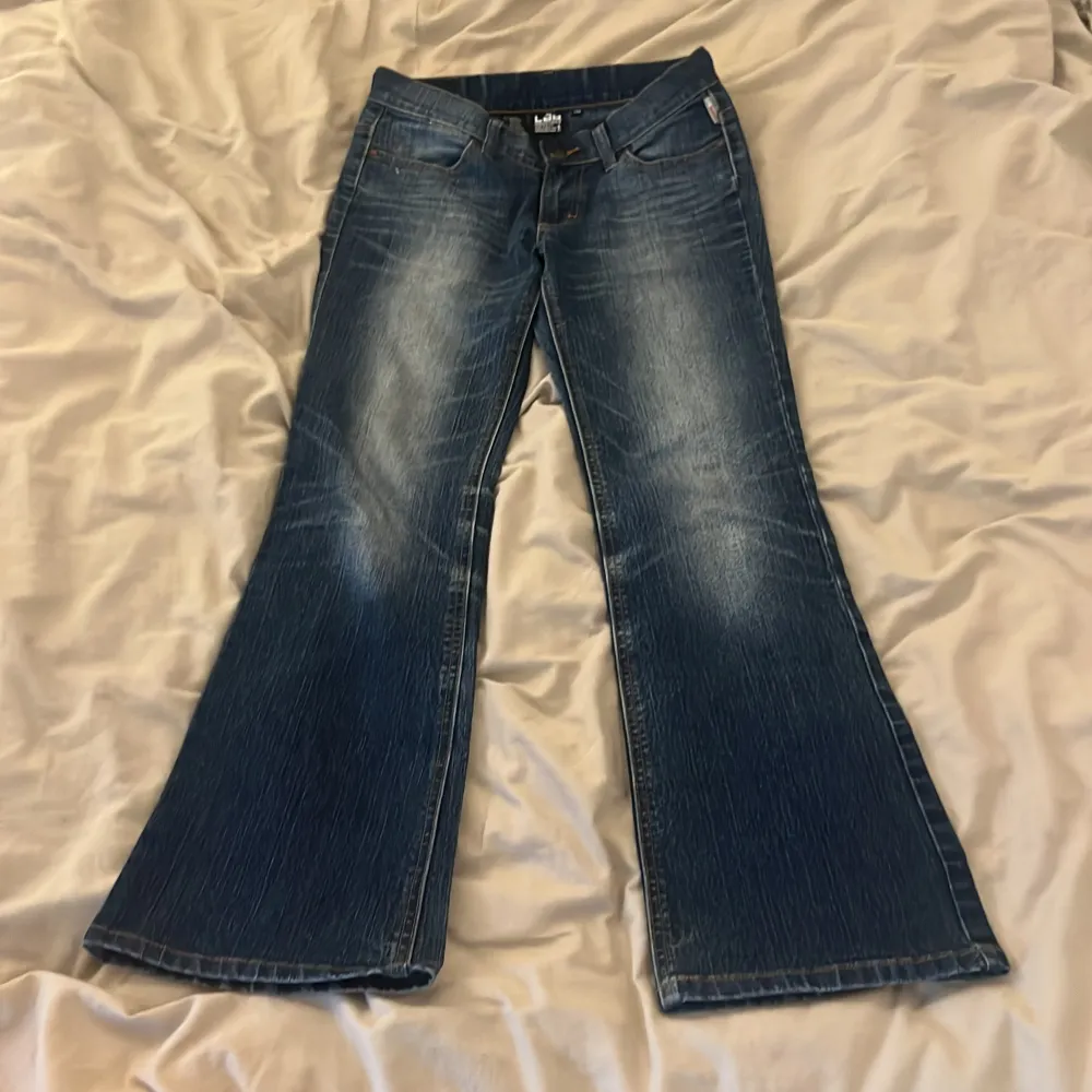 Snygga blå bootcut jeans från Lab Industries med klassisk femficksdesign och knappgylf. Jeansen har en lätt tvättad look och är perfekta för en avslappnad stil. De har en normal passform och är tillverkade i jeansmaterial.. Farkut & Housut.