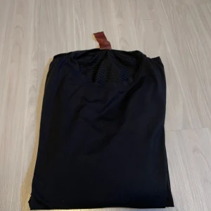 Svart tränings T-Shirt från newbody - Säljer en stilren svart t-shirt med korta ärmar. Perfekt för en enkel och avslappnad look. T-shirten har en rund hals och är tillverkad i ett mjukt material.