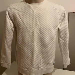 Vit tröja från Bondelid - Säljer en stilren vit tröja från Bondelid med ett unikt prickigt mönster. Tröjan har långa ärmar och en rund halsringning. Perfekt för en avslappnad och modern look. Passar bra till både jeans och chinos.