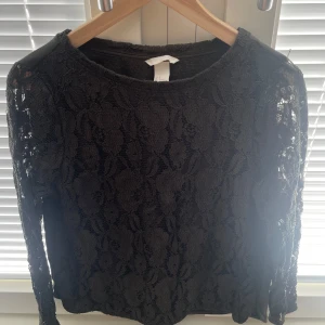 Grön spetsblus från H&M - Säljer en grön spetsblus från H&M. Blusen har långa ärmar och ett blommönster i spets på framsidan. Man ser färgen tydligast på sista bilden🤍
