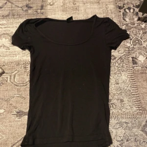 Svart kortärmad topp - Säljer en enkel och stilren svart kortärmad topp. Perfekt basplagg för alla tillfällen. Mjuk och bekväm att bära.