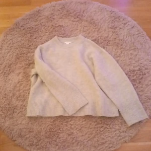 Beige stickad tröja från Gina Tricot - Mysig beige stickad tröja från Gina young. Tröjan har långa ärmar och en klassisk rund halsringning. Jätte fint skick men dock en jätte liten fläck på armbågen som knappt syns. Tror den går bort i tvättmaskin. Köpt för runt 300kr och är lite oversized💞