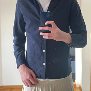 Mörkblå skjorta från Gabba - Snygg mörkblå skjorta från Gabba med klassisk krage och knappar framtill. Skjortan har långa ärmar och är perfekt för en stilren look. Tillverkad i ett mjukt material som ger en bekväm passform.