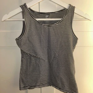 Randig linnetopp från H&M - Säljer en randig linnetopp från H&M i svart och vit. Toppen är ärmlös och gjord av ekologisk bomull, perfekt för en avslappnad stil. Passar bra till jeans eller shorts.