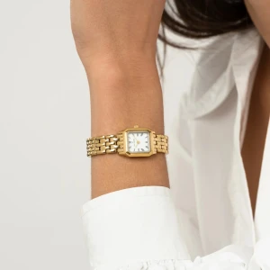 Aldrig använd mockberg klocka - Elegant guldfärgad klocka med fyrkantig urtavla och länkarmband. Urtavlan är vit med svarta visare och romerska siffror. Perfekt accessoar för en stilren look. Aldrig använd