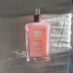Rose Shimmering Glow Oil - Rose Shimmering Glow Oil från Mikura Glow Care är en superåterfuktande kroppsolja med glittereffekt. Den ger huden en vacker lyster. Perfekt för normal och torr hud. Kommer i en elegant fyrkantig flaska med pipett för enkel applicering. OANVÄND. 