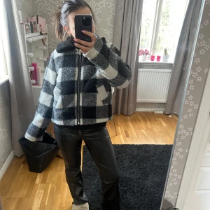 Rutig teddyjacka från NA-KD - Säljer en supermysig rutig teddyjacka från NA-KD i svart och vit. Jackan har en dragkedja framtill och en skön, fluffig känsla. Perfekt för kyliga dagar när du vill vara både varm och stilren. 🖤🤍