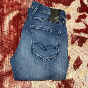 Blå jeans från Replay - Snygga blå jeans från Replay med klassisk femficksdesign och en diskret tvätt för en stilren look. De har en normal passform och är perfekta för en avslappnad stil. Märkeslogga på baksidan av midjan.