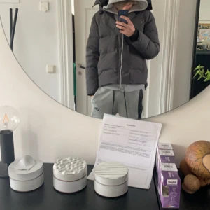 Grå dunjacka från Canada Goose - Säljer en grå dunjacka från Canada Goose med huva och dragkedja. Jackan har en broderad logotyp på ärmen och är perfekt för kalla dagar. Den är i storlek S och har en klassisk pufferdesign. Bra skick  perfekt till vinter och kalla dagar tag jack påsen med följer skriv om ni undrar något!