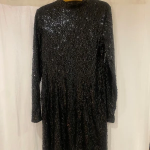 Svart paljettklänning från Gina Tricot - Snygg svart klänning från Gina Tricot täckt med glittriga paljetter. Perfekt för en kväll ute eller fest. Klänningen har långa ärmar och kort modell ✨