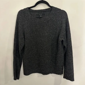 Mörkgrå stickad tröja - Säljer en mysig mörkgrå stickad tröja Tröjan har en rund halsringning och långa ärmar, perfekt för kyligare dagar. Enkel och stilren design som passar till det mesta. Perfekt för höst och vinter!