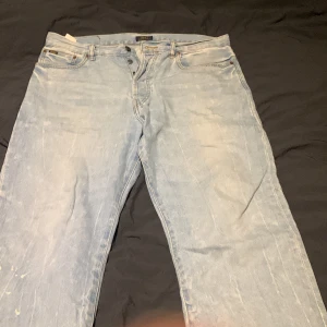 Ljusblå jeans från Polo Ralph Lauren - Säljer ett par ljusblå jeans från Polo Ralph Lauren. De har en klassisk tapered passform och är tillverkade i denim. Jeansen har en knappgylf och femficksdesign. Perfekta för en avslappnad stil.