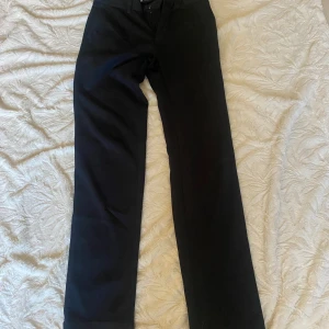 Mörkblå byxor med vida ben - Snygga mörkblå  byxor med vida ben och hög midja. Perfekta för en stilren look. Byxorna har en dragkedja och knappar framtill. Golf byxor. 