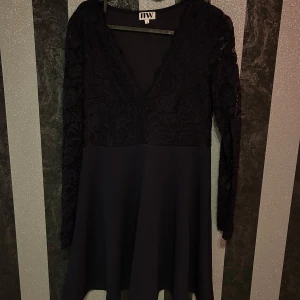  klänning med spetsdetaljer - Elegant svart/blå klänning med v-ringad spetsöverdel och långa ärmar. Storlek M. 