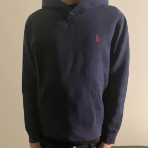 Mörkblå hoodie från Ralph Lauren - Säljer en stilren mörkblå hoodie från Ralph lauren.    Modellen är 170 och den sitter perfekt. Skicket är relativt bra därav priset.