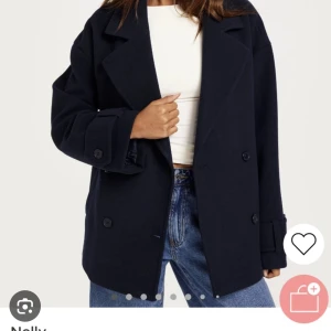 Mörkblå kappa från Nelly, nypris:699kr - Snygg mörkblå kappa från Nelly med dubbelknäppning och breda slag. Jackan har en avslappnad passform och långa ärmar med knappar vid ärmsluten. Perfekt för en stilren look.