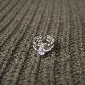 Heart Charm - Silver Ring with Stone - US storlek 7, diameter 17,3 mm, omkrets 54,4 mm. En romantisk ring som förenar elegans och charm. Det hjärtliga motivet med en gnistrande sten ger en sofistikerad och personlig touch, medan den justerbara designen gör att den passar perfekt för varje tillfälle.
