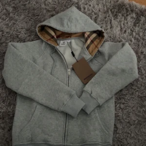Grå huvtröja från Burberry - Säljer en grå huvtröja från Burberry helt ny kan sälja för 600-500kr